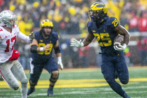 Michigan running back Hassan Haskins (25) rushes as Ohio State safety Bryson Shaw (17) chases in the fourth quarter of an NCAA college football game in Ann Arbor, Mich., Saturday, Nov. 27, 2021. (AP Photo/Tony Ding)