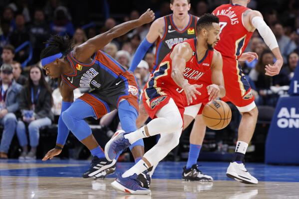 New Orleans Pelicans guard CJ McCollum, front right, drives the ball away from Oklahoma City Thunder guard Luguentz Dort (5) during the first half of an NBA basketball game Friday, Dec. 23, 2022, in Oklahoma City. (AP Photo/Garett Fisbeck)