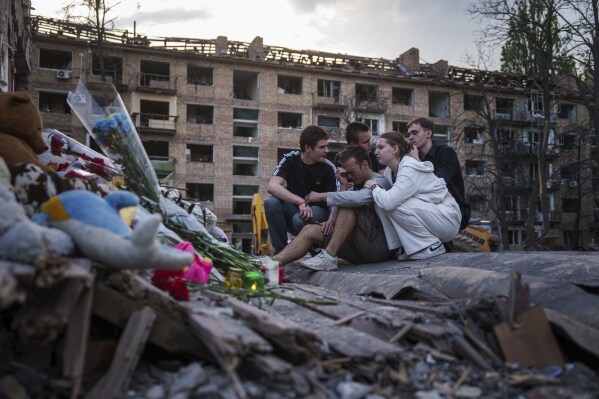 Friends of Danylo Khudia, 17, who was killed on Thursday by a Russian strike, gather near the rubble of a house in a residential neighborhood in Kyiv, Ukraine, on Friday, April 25, 2025. (AP Photo/Evgeniy Maloletka, File)