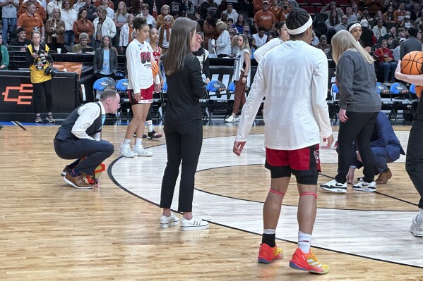 A person measures the 3-point line as North Carolina State warms up before an Elite Eight college basketball game against Texas in the women's NCAA Tournament, Sunday, March 31, 2024, in Portland, Ore. The 3-point line for the women's NCAA Tournament at Moda Center had a discrepancy in distance at each end of the court that went unnoticed through four games over two days before Texas and North Carolina State were informed of the problem ahead of their Elite Eight matchup on Sunday. (AP Photo/Anne Peterson)