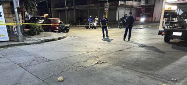 This photo provided by the Public Information Office, National Capital Region Police Office shows investigators at the site where New Zealander Nicholas Peter Stacey was shot by suspected robbers in Makati, Philippines on Sunday Feb. 19, 2023. A massive Philippine police search was underway on Wednesday for two motorcycle-riding men who shot and killed the New Zealand man in a brazen street robbery that officials fear could scare foreign tourists away. (Public Information Office, National Capital Region Police Office via AP)