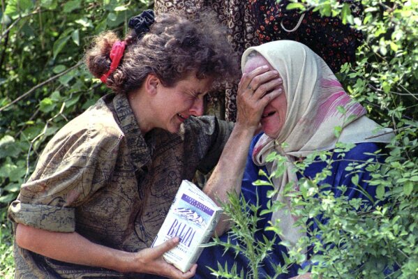 FILE- In this Thursday, July 13, 1995, file picture a woman and her mother, refugees from Srebrenica, cry worried about the fate of the rest of their family, after reaching a U.N. base near Tuzla, Bosnia. Survivors of the genocide in the eastern Bosnian town of Srebrenica, mainly women, will on Saturday July 11, 2020, commemorate the 25th anniversary of the slaughter of their fathers and brothers, husbands and sons. The slaughter was the only atrocity of the brutal war that has been confirmed an act of genocide.(AP Photo/Darko Bandic, File)