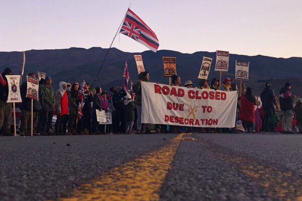 FILE - In this July 15, 2019, file photo, demonstrators block a road at the base of Hawaii's tallest mountain, in Mauna Kea, Hawaii, to protest the construction of a giant telescope on land that some Native Hawaiians consider sacred. The University of Hawaii's board is forming a task force to study the school's management of Mauna Kea's summit, which is currently at the center of long-running protests against the construction of a new telescope. (AP Photo/Caleb Jones)