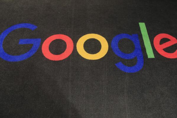 FILE - The logo of Google is displayed on a carpet at the entrance hall of Google France in Paris, Nov. 18, 2019.  Google’s digital advertising empire turned in another strong performance during the holiday shopping season, propelling a 36% increase in its corporate parent’s revenue during the final three months of 2021. (AP Photo/Michel Euler, File)