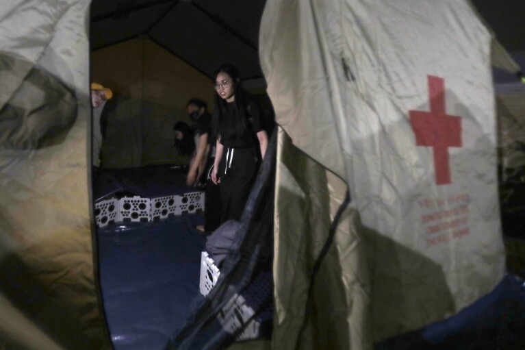 People evacuated from their homes sit in the tent area of ​​a shelter after the main earthquake struck in Hualien City, eastern Taiwan, early Thursday morning, April 4, 2024. The strongest earthquake in a quarter of a century hit Taiwan during the morning rush hour.  (AP Photo/Chiang Ying-ying)