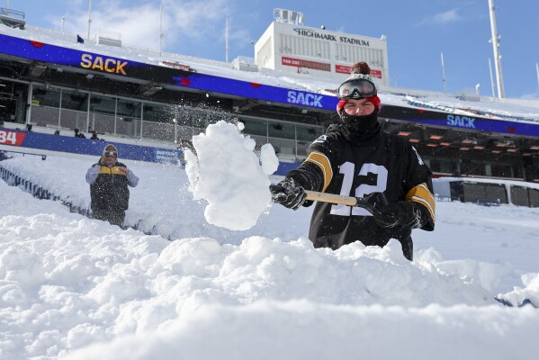 A Pittsburgh Steelers fan clears snow from his row of seats before an NFL wild-card playoff football game between the Buffalo Bills and the Pittsburgh Steelers, Monday, Jan. 15, 2024, in Buffalo, N.Y. (AP Photo/Jeffrey T. Barnes)