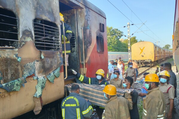 Firefighters hold a stretcher to carry bodies from a train coach where fire erupted in Madurai, in the southern Indian state of Tamil Nadu, Satursday, Aug. 26, 2023. A gas cylinder smuggled in by some passengers caused the fire killing nine people, according to a statement by the Southern Railway. (AP Photo)