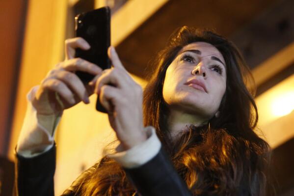 FILE - Lebanese Journalist Dima Sadek uses her cellphone to make a video of an anti-government protest, in Beirut, Lebanon, Dec. 4, 2019. The stabbing of author Salman Rushdie on Friday, Aug. 12, 20222 in western New York, has laid bare the divisions within Lebanon’s Shiite community of which some have expressed support for the act while others harshly criticized it leading to death threats against Sadek, a prominent journalist. The assailant, 24-year-old Hadi Matar, is a dual Lebanese-U.S. citizen, and his father lives in a village in Hezbollah-dominated southern Lebanon. (AP Photo/Hussein Malla, File)