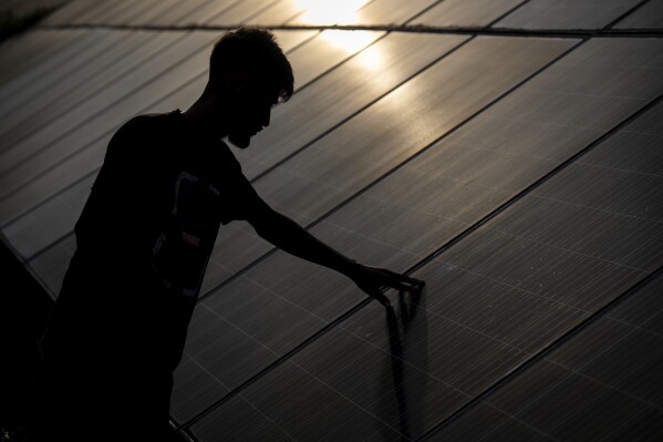 An employee checks solar panels near a hydrogen plant at Oil India Limited in Jorhat, India, Thursday, Aug. 17, 2023. (AP Photo/Anupam Nath)