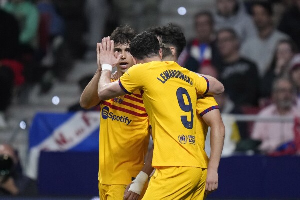 Barcelona's Joao Felix, left, celebrates with his teammates after scoring his side's opening goal during the La Liga soccer match between Atletico Madrid and Barcelona at the Metropolitano stadium in Madrid, Spain, Sunday, March 17, 2024. (AP Photo/Bernat Armangue)