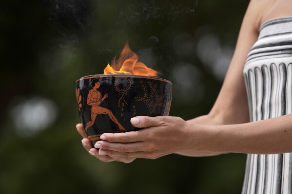 Um artista segura um pote de cerâmica com a chama durante a cerimônia oficial de acendimento da chama das Olimpíadas de Paris, no local da Antiga Olímpia, Grécia, terça-feira, 16 de abril de 2024. (AP Photo/Thanassis Stavrakis)