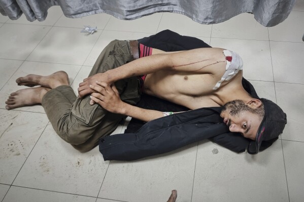 An injured man waits for treatment on the floor of a hospital following Israeli airstrikes in Khan Younis, southern Gaza Strip, Tuesday, March 18, 2025. (AP Photo/Mohammad Jahjouh, File)