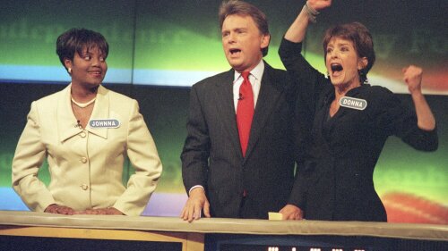 FILE - Johnna Goodwin, left, watches as Donna Handel, right, reacts after winning on "Wheel of Fortune," with host Pat Sajak during a taping of the game show in Philadelphia on April 17, 1999. The game show was in Philadelphia for the weekend taping a week's worth of shows. Ryan Seacrest will replace the retiring Sajak as host of “Wheel of Fortune.” (AP Photo/William Thomas Cain, File)