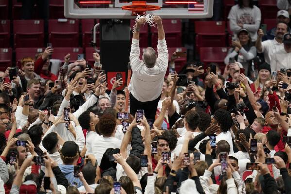 San Diego State head coach Brian Dutcher falls back from a ladder onto his players after San Diego State defeated Wyoming in an NCAA college basketball game to win the Mountain West Conference Saturday, March 4, 2023, in San Diego. (AP Photo/Gregory Bull)