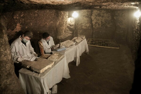 
              Archaeologists work on statues and artifacts inside a tomb, at an ancient necropolis near Egypt's famed pyramids in Saqqara, Giza, Egypt, Saturday, Nov. 10, 2018. A top Egyptian antiquities official says local archaeologists have discovered seven Pharaonic Age tombs near the capital Cairo containing dozens of cat mummies along with wooden statues depicting other animals. (AP Photo/Nariman El-Mofty)
            