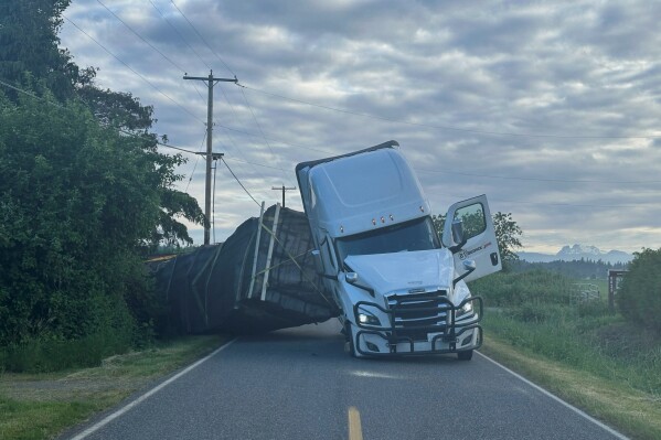 This image taken from video provided by Whatcom County Sheriff's Office shows a truck hauling an estimated 70,000 pounds of honeybee hives overturn on Friday, May 30, 2025 near Lynden, Wash. (Whatcom County Sheriff's Office via AP)