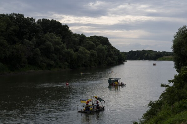 Volunteers paddle their boats on the Tisza River as they participate in Plastic Cup event, where they scour Hungary's second-largest river for trash on Tuesday, Aug. 1, 2023. (AP Photo/Denes Erdos)