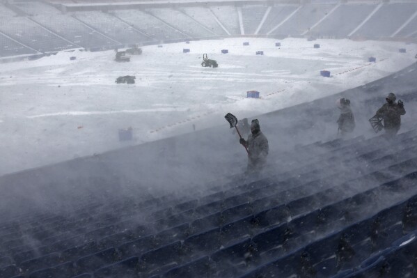 Workers remove snow from Highmark Stadium in Orchard Park, N.Y., Sunday Jan. 14, 2024. A potentially dangerous snowstorm that hit the Buffalo region on Saturday led the NFL to push back the Bills wild-card playoff game against the Pittsburgh Steelers from Sunday to Monday. New York Gov. Kathy Hochul and the NFL cited public safety concerns for the postponement, with up to 2 feet of snow projected to fall on the region over a 24- plus hour period. (AP Photo/ Jeffrey T. Barnes)