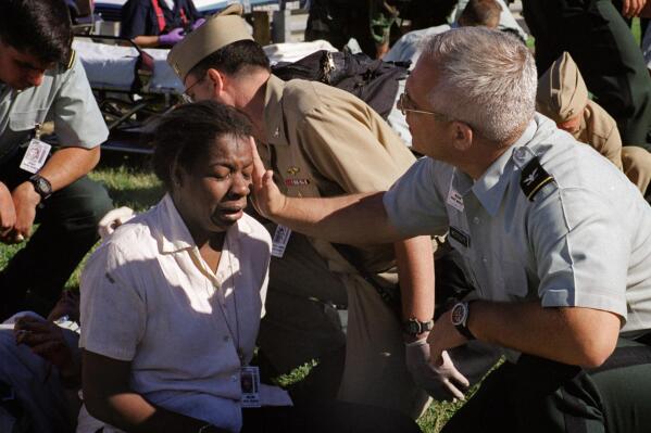 Deputy chief of the Army Reserve, Col. Malcolm Bruce Westcott, comforts Pentagon employee Racquel Kelley while giving her medical aid outside the Pentagon in Washington on Tuesday, Sept. 11, 2001. (AP Photo/Will Morris)
