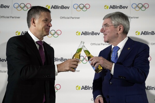 Anheuser-Busch InBev CEO Michel Doukeris, left, and President of the IOC Thomas Bach attend a news conference in London, Friday, Jan. 12, 2024. The International Olympic Committee has signed Anheuser-Busch InBev as the first beer brand in the 40-year history of its sponsorship program, which earns billions of dollars for the organization and international sports. (AP Photo/Kin Cheung)
