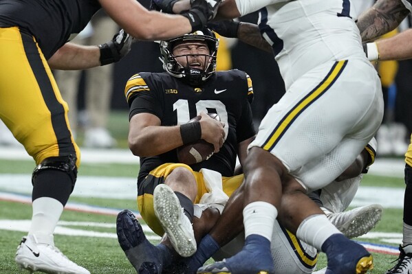 Iowa quarterback Deacon Hill (10) is sacked during the first half of the Big Ten championship NCAA college football game against Michigan, Saturday, Dec. 2, 2023, in Indianapolis. (AP Photo/Darron Cummings)