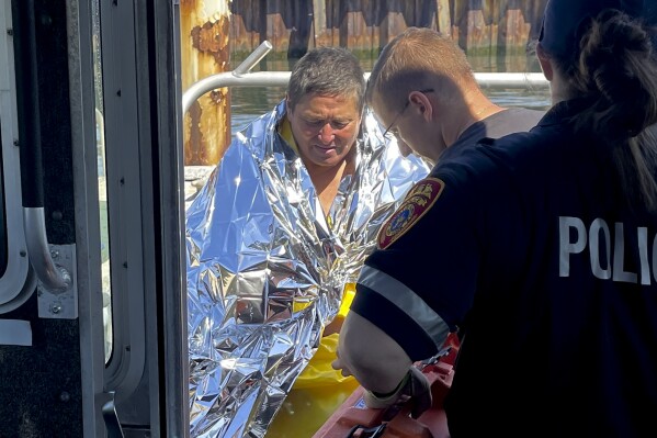 This image provided by Suffolk County Police shows Dan Ho, left, being treated by medics after having been rescued after treading water for five hours in the Atlantic Ocean off the coast of Long Island, Monday, July 31, 2023, in Babylon, N.Y. Suffolk County Police say that the 63-year-old went swimming at a beach in Babylon at around 5 a.m. Monday and was pulled out to open water by the current. (Courtesy of the Suffolk County Police via AP)