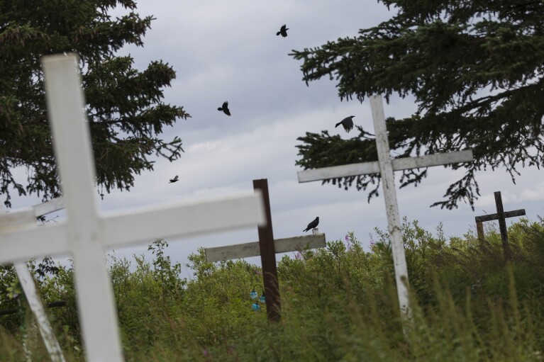 Ravens fly across the horizon along the village cemetery, Saturday, Aug. 19, 2023, in Akiachak, Alaska. (AP Photo/Tom Brenner)