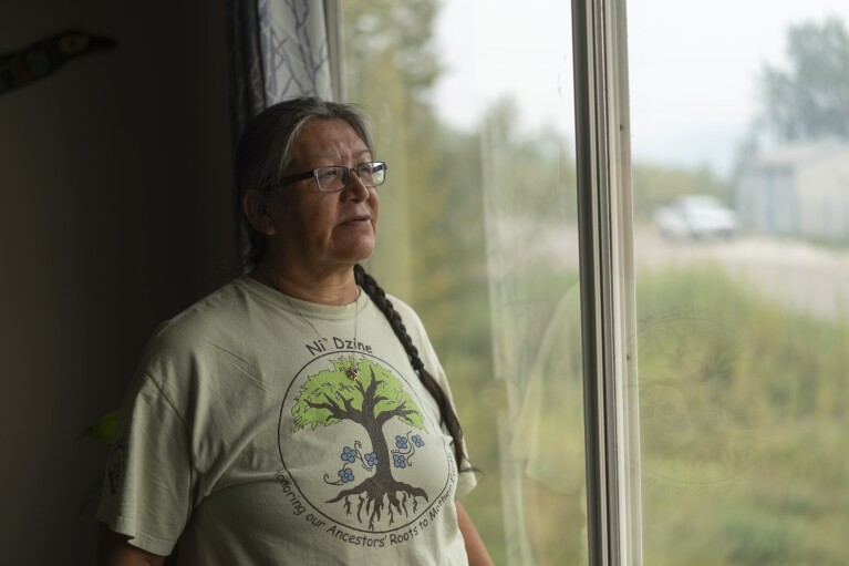 Jean L'Hommecourt, an environmental advocate and member of the Fort McKay First Nation, looks out of her window on a smokey day due to wildfires in Fort McKay, Canada, on Saturday, Sep. 2, 2023. (AP Photo/Victor R. Caivano)