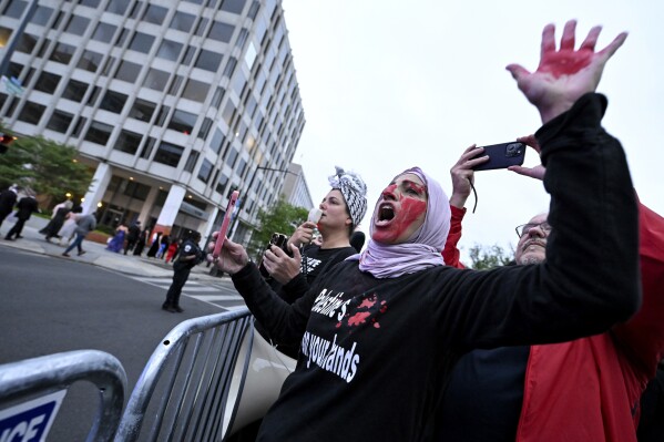 Um manifestante com as mãos e o rosto pintados de vermelho é visto atrás de uma barricada policial durante uma manifestação pró-Palestina contra a guerra Israel-Hamas no jantar da Associação de Correspondentes da Casa Branca em Washington, sábado, 27 de abril de 2024.  (Foto AP / Terrence Williams)