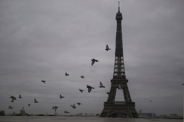 Pigeons fly next to the Eiffel Tower in Paris, Friday, Oct. 30, 2020. France re-imposed a monthlong nationwide lockdown Friday aimed at slowing the spread of the virus, closing all non-essential business and forbidding people from going beyond one kilometer from their homes except to go to school or a few other essential reasons. (AP Photo/Thibault Camus)
