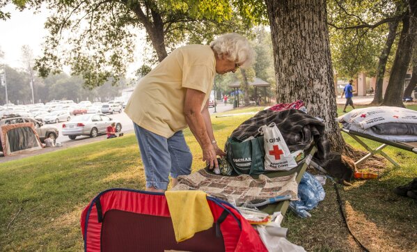 
              Carol Bershers, 75, of the city of Shasta Lake, sorts her clothes at the Shasta College evacuation center, in Redding, Calif., Sunday, July 29, 2018, where she and her husband, Otis, and cat Smokey have been sleeping since Thursday after they were evacuated because of wildfires. (Hector Amezcua/The Sacramento Bee via AP)
            