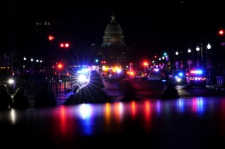 FILE - In this Wednesday, Jan. 6, 2021, file photo, with the U.S. Capitol in the background, lights from police vehicles illuminate Pennsylvania Avenue in Washington, following an insurrection. Federal agents have accused an Arkansas man of beating a police officer with a pole flying a U.S. flag during the Jan. 6 riot at the U.S. Capitol. (AP Photo/Carolyn Kaster, File)