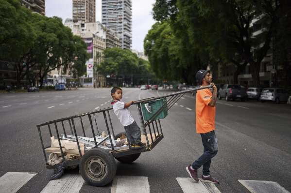 Elias Fernandez, accompanied by his son Juan, pulls the cart he uses to collect recyclables to sell, in Buenos Aires, Argentina, Tuesday, Feb. 4, 2025. (AP Photo/Rodrigo Abd)