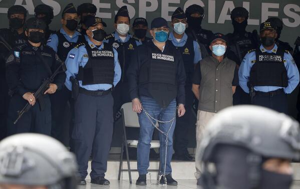 Former Honduran President Juan Orlando Hernandez, center in chains, is shown to the press at the Police Headquarters in Tegucigalpa, Honduras, Tuesday, Feb. 15, 2022. Police arrested Hernandez at his home, following a request by the United States government for his extradition on drug trafficking and weapons charges. (AP Photo/Elmer Martinez)