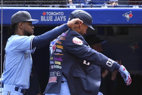 Toronto Blue Jays center-fielder George Springer, right, receives the home run jacket from Otto Lopez, after hitting a solo home run against the New York Yankees batter in fifth inning of a baseball game in Toronto, Sunday, June 19, 2022. (Jon Blacker/The Canadian Press via AP)