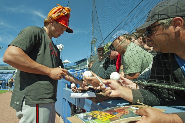 Baltimore Orioles second baseman Jackson Holliday signs autographs before a spring training game against the Toronto Blue Jays, Tuesday, March 19, 2024, in Dunedin, Fla. (Mark Taylor/The Canadian Press via AP)