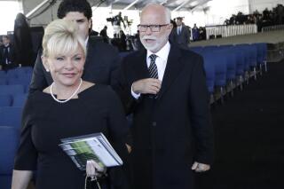 FILE - In this March 2, 2018 file photo, Televangelist Jim Bakker, right, walks with his wife Lori Beth Graham after a funeral service at the Billy Graham Library for the Rev. Billy Graham, in Charlotte, N.C. Jim Bakker and his southwestern Missouri church will pay restitution of $156,000 to settle a lawsuit that accused the TV pastor of falsely claiming that a health supplement could cure the coronavirus. Missouri court records show that a settlement agreement was filed Tuesday, June 22, 2021. (AP Photo/Chuck Burton File)