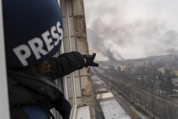 Associated Press photographer Evgeniy Maloletka points at the smoke rising after an airstrike on a maternity hospital, in Mariupol, Ukraine, Wednesday, March 9, 2022. (AP Photo/Mstyslav Chernov)