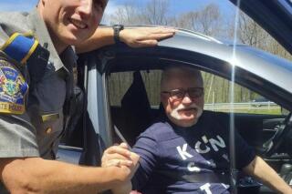 In this photo provided by the Connecticut State Police, Trooper Lukasz Lipert shakes hands with former Polish President Lech Walesa on Interstate 84 in Tolland, Conn., on Wednesday, May 11, 2022. State police said Lipert responded to the call of an SUV with a flat tire, and was greeted by Walesa, who had spoken in Hartford on Tuesday as part of his U.S. tour advocating for aid for refugees who have fled Ukraine during the war with Russia. (Connecticut State Police via AP)