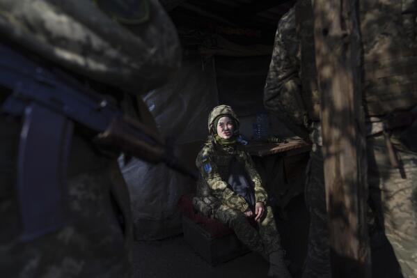 A Ukrainian soldier talks with her comrades sitting in a shelter at the line of separation between Ukraine-held territory and rebel-held territory near Svitlodarsk, eastern Ukraine, Wednesday, Feb. 23, 2022. U.S. President Joe Biden announced the U.S. was ordering heavy financial sanctions against Russia, declaring that Moscow had flagrantly violated international law in what he called the "beginning of a Russian invasion of Ukraine." (AP Photo/Evgeniy Maloletka)