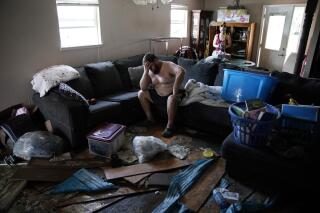 Josh Montford rests his head in his hand while going through his flood damaged home in the aftermath of Hurricane Ida, on Sept. 1, 2021, in Jean Lafitte, La. "I'm overwhelmed," said Montford as he searched for items to salvage. (AP Photo/John Locher)