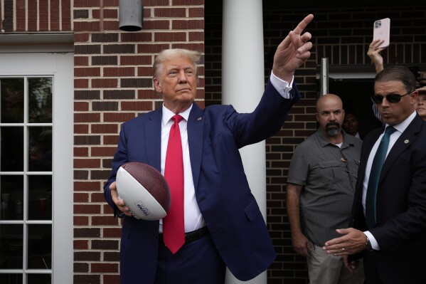 Former President Donald Trump holds a football before throwing it to the crowd during a visit to the Alpha Gamma Rho, agricultural fraternity, at Iowa State University before an NCAA college football game between Iowa State and Iowa, Saturday, Sept. 9, 2023, in Ames, Iowa. (AP Photo/Charlie Neibergall)