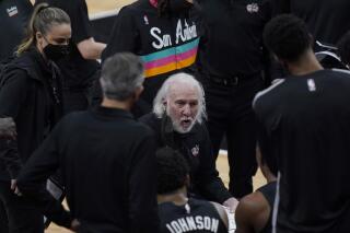 San Antonio Spurs head coach Gregg Popovich, center, talks to his players during a timeout in the first half of an NBA basketball game against the Phoenix Suns in San Antonio, Sunday, May 16, 2021. (AP Photo/Eric Gay)