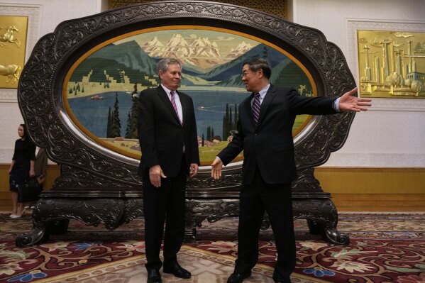 Chinese Vice Premier He Lifeng, right, shows the way for U.S. Sen. Steve Daines before a meeting held in the Xinjiang Room at the Great Hall of the People in Beijing, China, Saturday, March 22, 2025. (AP Photo/Ng Han Guan, Pool)