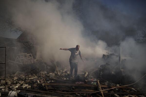 A man walks on the debris of a burning house, destroyed after a Russian attack in Kharkiv, Ukraine, Thursday, March 24, 2022. (AP Photo/Felipe Dana)