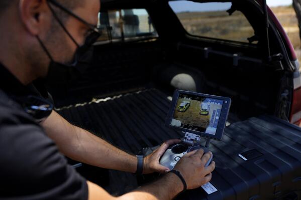 A British police officer controls a drone with cameras within the British military base, between Greek Cypriot, south, and Turkish Cypriots, north, near Dhekelia military base, in Cyprus, Tuesday, July 6, 2021. 
Authorities at a British military base on Cyprus have doubled their customs officers and procured detection equipment as part of stepped-up efforts to thwart people trafficking from the breakaway north of the ethnically split island nation. (AP Photo/Petros Karadjias)