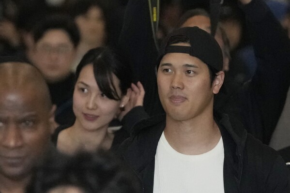Los Angeles Dodgers' Shohei Ohtani and his wife Mamiko Tanaka walk with security during the baseball team's arrival at Incheon International Airport, Friday, March 15, 2024, in Incheon, South Korea, ahead of the team's baseball series against the San Diego Padres. (AP Photo/Lee Jin-man)