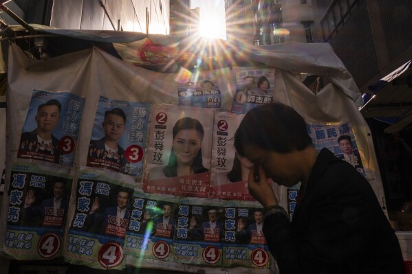 A pedestrian passes by banners promoting candidates for upcoming district council elections in Hong Kong, Tuesday, Nov. 28, 2023. (APPhoto/Louise Delmotte)