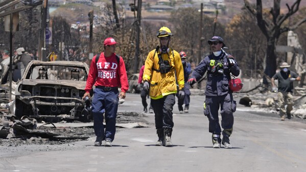 FILE - Members of a search-and-rescue team walk along a street, Saturday, Aug. 12, 2023, in Lahaina, Hawaii, following heavy damage caused by wildfire. (AP Photo/Rick Bowmer, File)