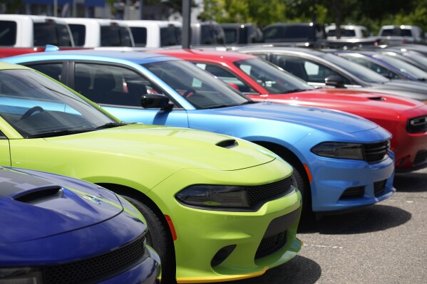 File - Unsold 2023 Charger sedans and Challenger hardtops sit at a Dodge dealership on June 18, 2023, in Littleton, Colo. Undeterred by high prices, rising interest rates, autoworker strikes and a computer chip shortage that slowed assembly lines, American consumers still bought 15.5 million new vehicles last year, 11% more than in 2022. (AP Photo/David Zalubowski, File)